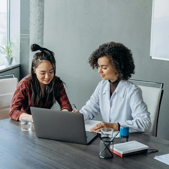 Two colleagues planning together at a laptop in a meeting room