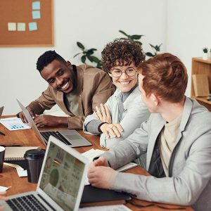 Three colleagues collaborating over laptops in an open-plan office